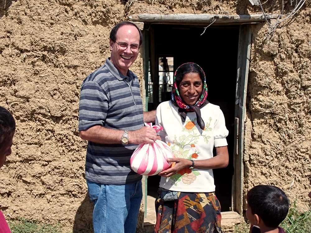 John Fenlason, co-founder of Kids in Crisis, handing a gift to a mother outside her home in Lazareni